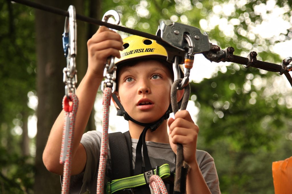 Boy fixing hooks to a climbing rope